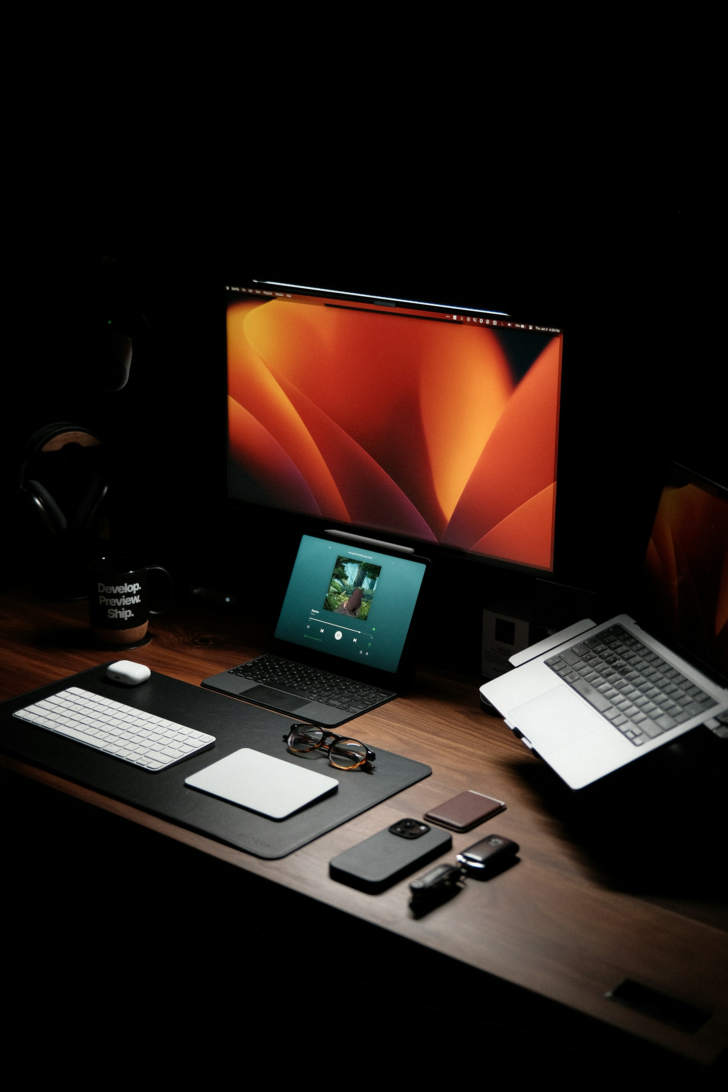 Creative workspace with monitor, tablet, laptop and keyboard on a dark wooden desk