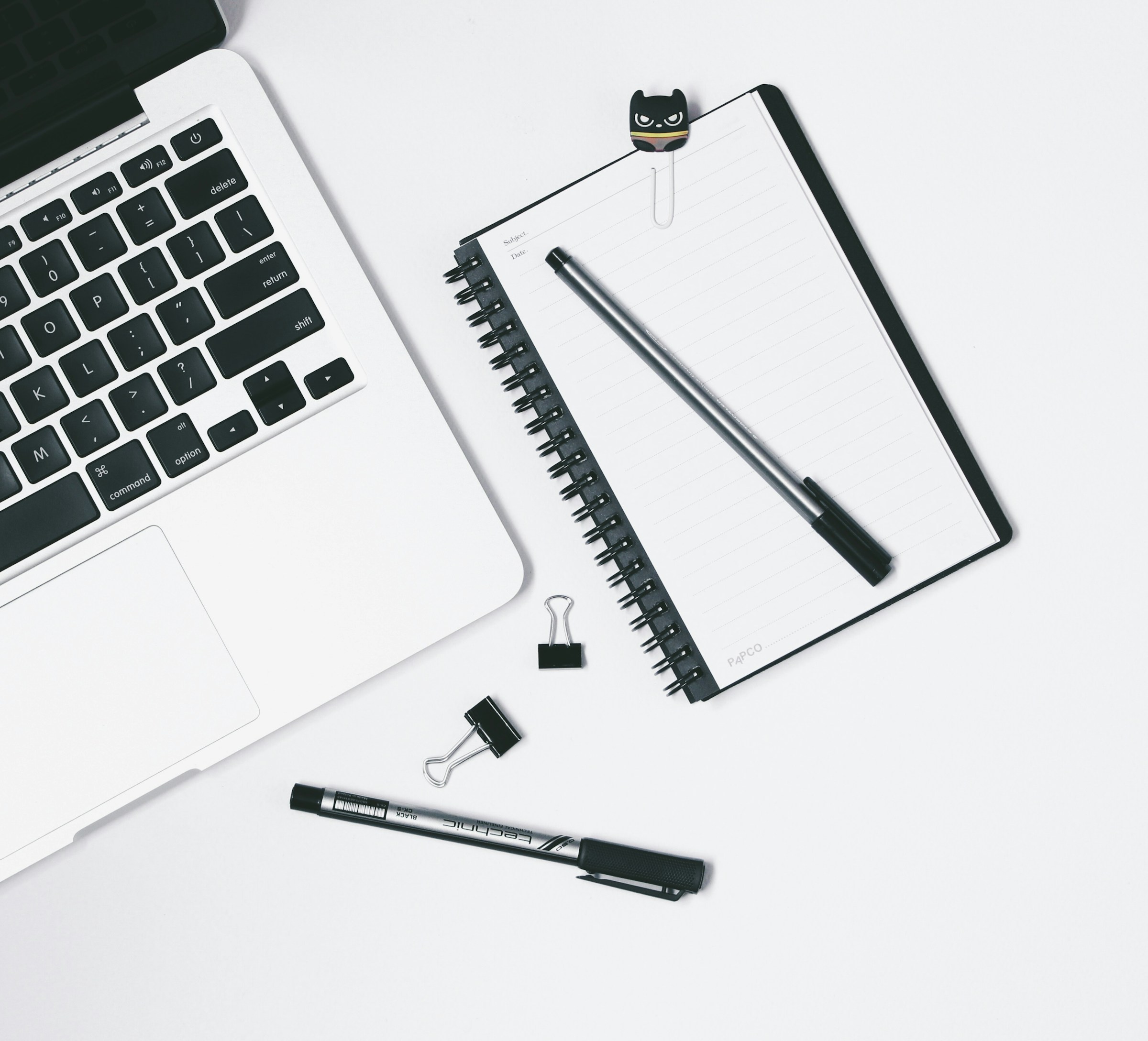 Laptop and spiral notebook on a white desk